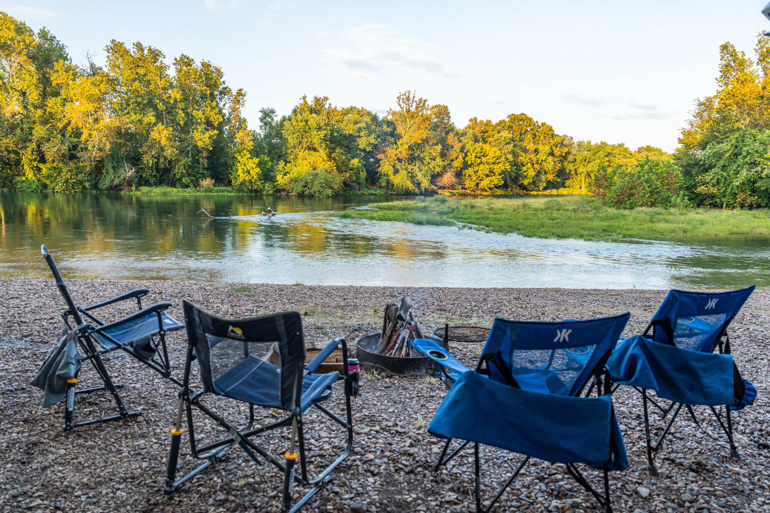 four camping chairs centered around a campfire facing the lower Illinois River
